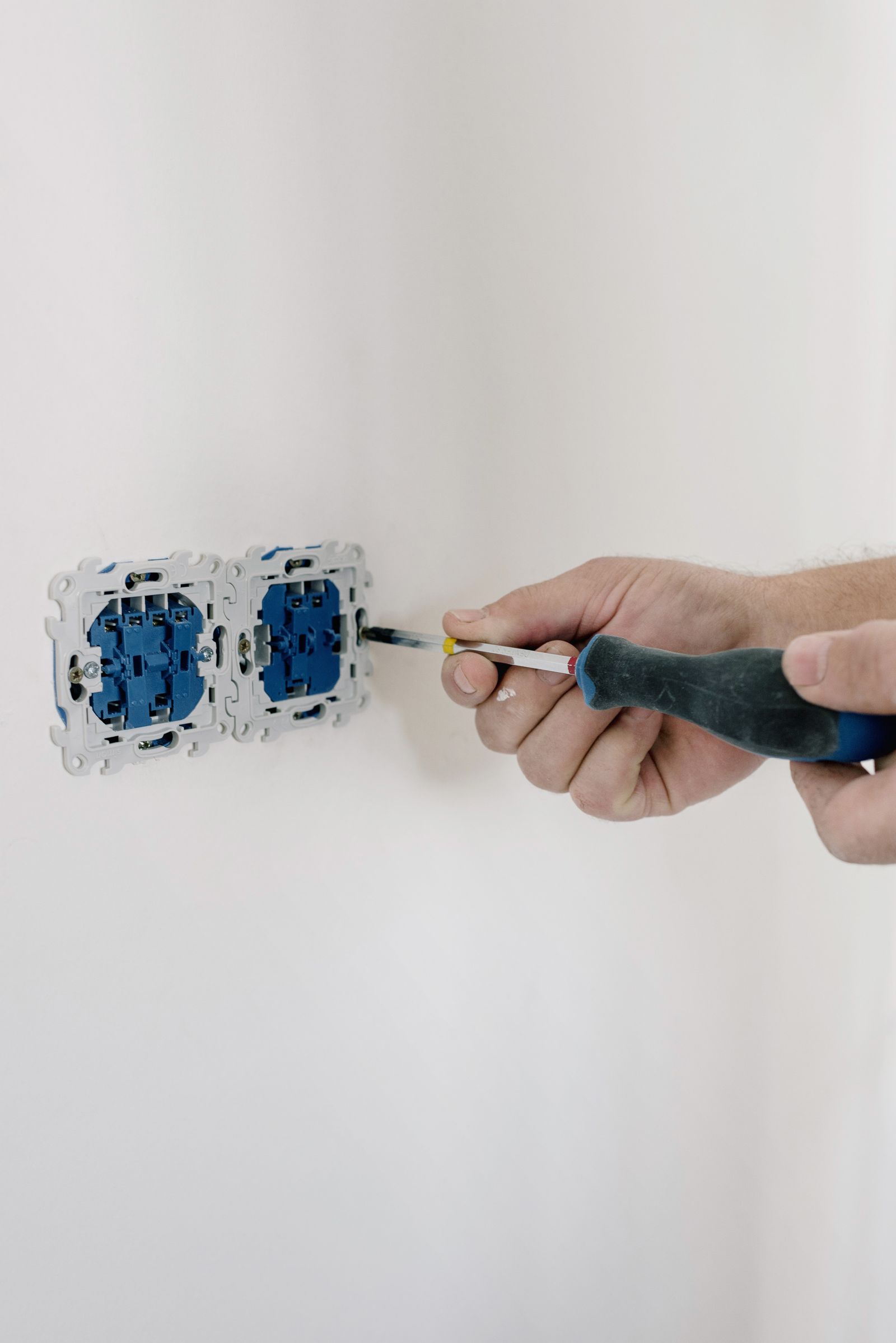 Electrician fitting a socket neatly on a freshly painted wall